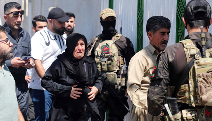 The mother (centre) and father (2-right) of one of two women journalists killed in a drone strike walk past Kurdish Asayish security forces as relatives and journalists gather in front of the forensic department where the bodies of the two women were brought, in Sulaimaniyah in Iraqs autonomous Kurdistan region on August 23, 2024. — AFP