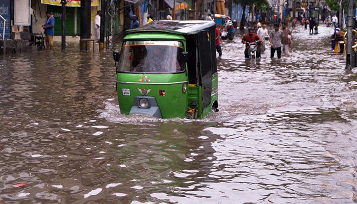 A rickshaw driver steers through accumulated rainwater at Lakshmi Chowk after record-breaking downpours hit Lahore on August 1, 2024. — APP