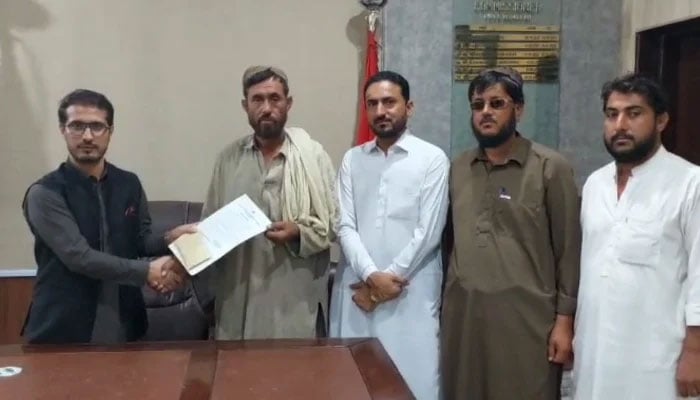 Killa Abdullah Deputy Commissioner Abdullah Farooq is handing over an appreciation certificate and cash prize to the excavator operator, Mohibullah on August 24, 2024. —Reporter