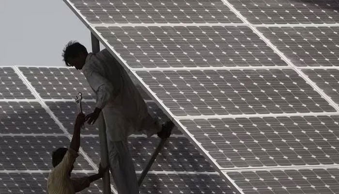 Technicians work on a solar panel at a power station near Karachi. — Reuters/File