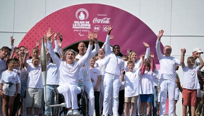 Former French wheelchair fencer Emmanuelle Assmann (C-L) with the torch of the Paris 2024 Paralympic Games on her wheelchair and other torchbearers during the arrival of the Paralympics flame at the entrance of the Channel Tunnel in Coquelles, northern France on Aug. 25, 2024. — AFP