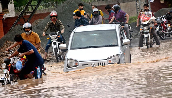 A car is trapped in a flooded road after record-breaking rains hit Lahore. — APP/File