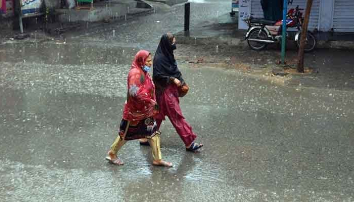 Women passing through a road during heavy rain on March 24, 2023. — Online