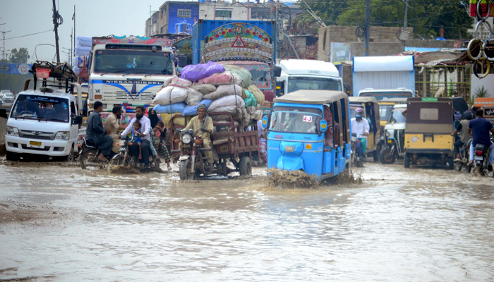 Vehicles pass through inundated Liaquatabad road after rain in Karachi on August 27, 2024. — PPI