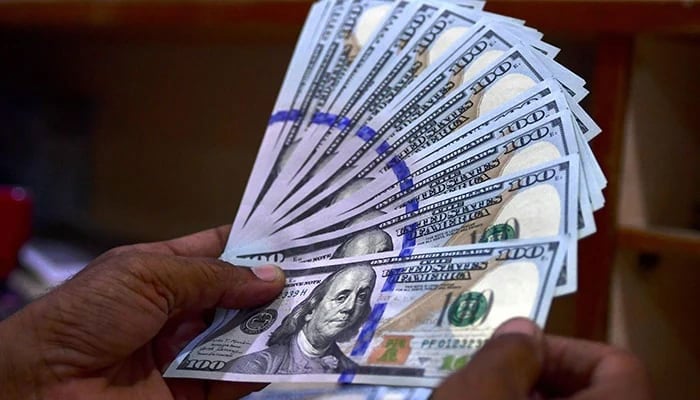 A foreign currency dealer counts US dollar notes at a currency market in Karachi on July 19, 2022. — AFP