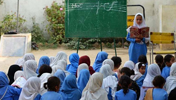 This representational image shows a girl student reading book before her class-mates. — AFP/File