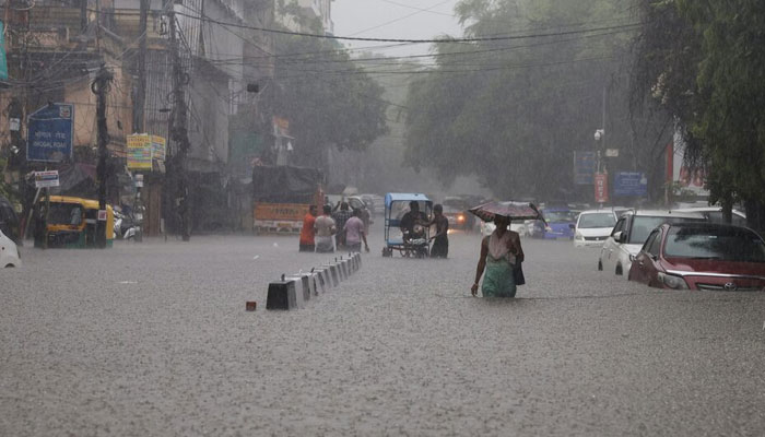 People wade through a flooded street after heavy rains in New Delhi, India on July 8, 2023. — Reuters