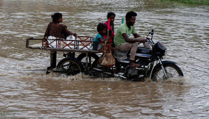 A family crosses a flooded street after heavy rains in Ahmedabad, India, August 28, 2024. — Reuters