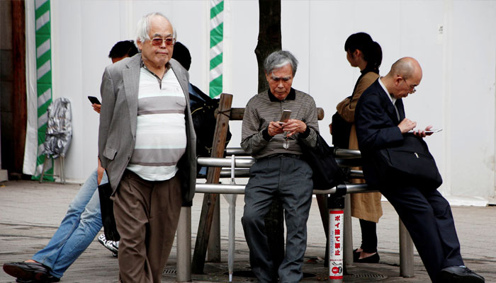 An elderly man uses a mobile phone in front a station in Tokyo, Japan, October 11, 2018. — Reuters