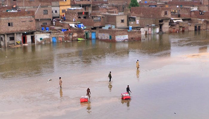 Rain effected people passing through accumulated rain water as new heavy spell of monsoon hits the city at Jinnah Colony Latifabad, Hyderabad . — APP