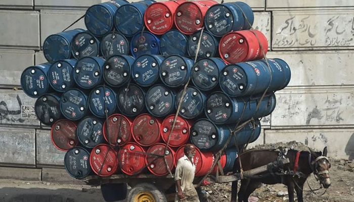 A man stands next to a horsecart laden with oil and petrol drums on a street. — AFP/File