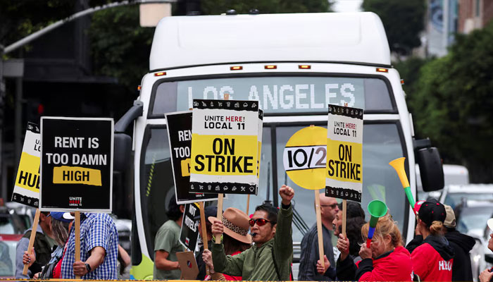 Hotel workers march and protest, while a bus driver waits to cross the road, as they continue their strike in Los Angeles, California, US, October 25, 2023. — Reuters