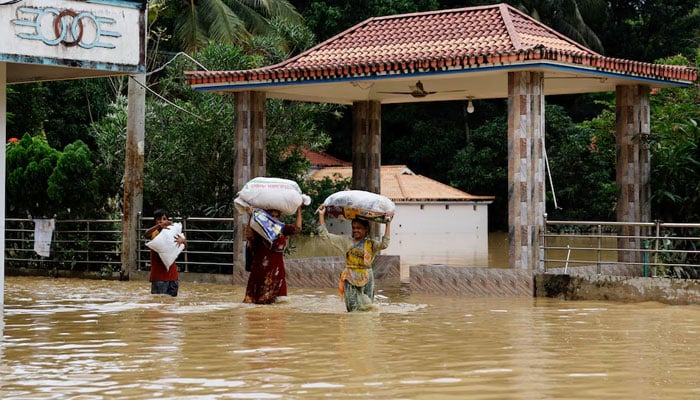 People carrying sacks, wade through flood water, amid severe flooding in the Fazilpur area of Feni, Bangladesh on  August 26, 2024. — Reuters