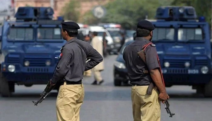 Sindh police personnel stand guard on the road. — APP/File