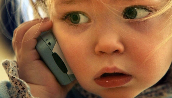 A toddler plays with a phone. — AFP/File