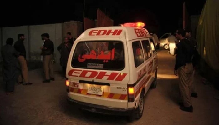 This image shows an Edhi ambulance passing by police officials. — AFP/File