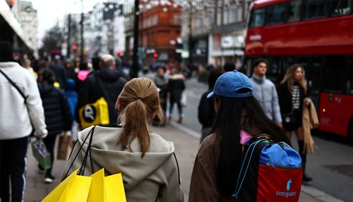 Shoppers carry their shopping bags along Oxford Street during the Boxing Day sales in London on December 26, 2023. — AFP