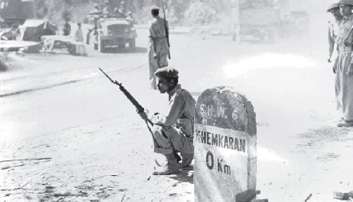 A soldier sitting near a sign block with Khem Kharan on it. — The News/file