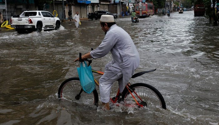 A man rides bicycle along a flooded road following heavy rains during the monsoon season in Karachi. — Reuters/File