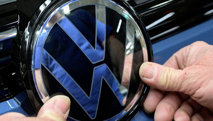 Volkswagen logo is fixed by an employee on a production line for the Golf VIII and Tiguan cars at the VW headquarters in Wolfsburg, Germany May 23, 2024. — Reuters