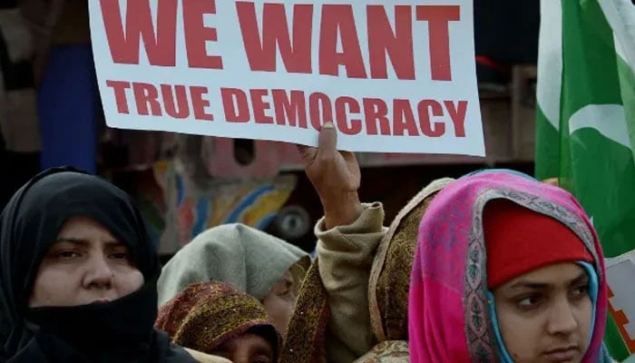 Women hold placards of democracy in their hands. — AFP/File