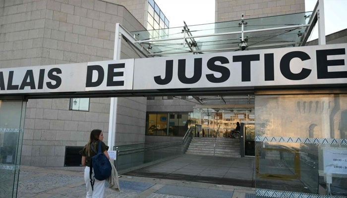 A woman arrives at the courthouse before the trial of a man accused of drugging his wife for nearly ten years and inviting strangers to rape her at their home in the south of France. — AFP