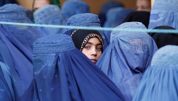 A girl looks on among Afghan women lining up to receive relief assistance, during the holy month of Ramadan in Jalalabad, Afghanistan, June 11, 2017. — Reuters