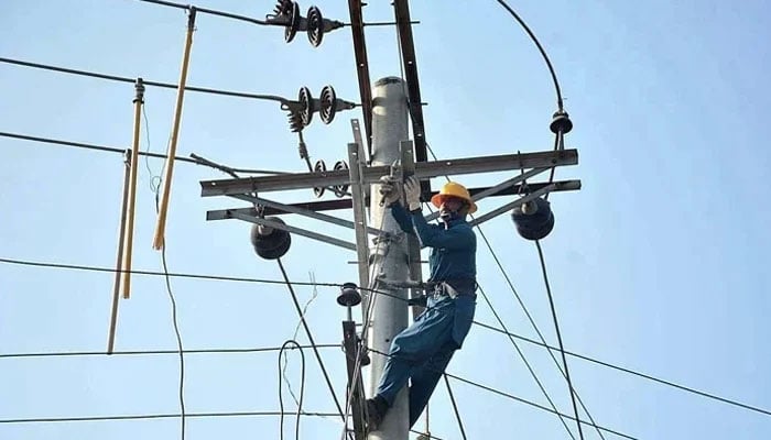 A electricity company worker fixes a line on an electric pole on December 19, 2022. — APP