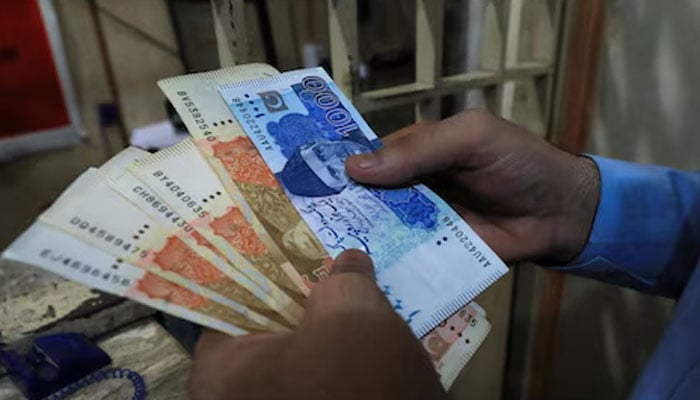 A man counts Pakistani rupee notes at a currency exchange shop in Peshawar. — Reuters/File