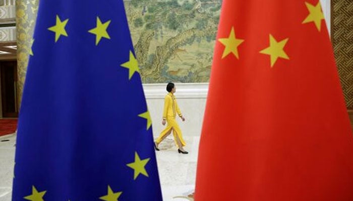 An attendant walks past flags of EU and China ahead of the EU-China High-level Economic Dialogue at Diaoyutai State Guesthouse in Beijing, China June 25, 2018. — Reuters