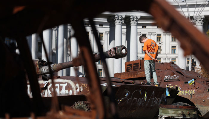 A boy stands on a destroyed Russian tank on display at Mykhailivska Square in Kyiv, on September 7, 2024. — AFP