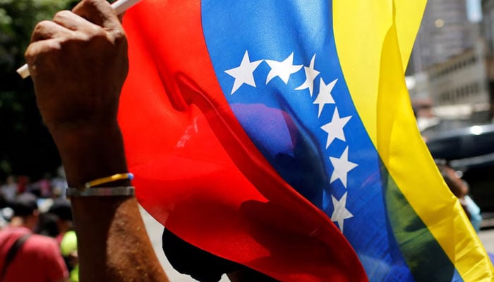 A supporter of Venezuelas President Nicolas Maduro holds a Venezuelan flag during the May Day celebrations in Caracas, Venezuela on May 1, 2022. — Reuters