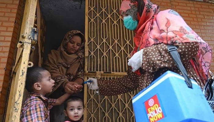 A health worker (R) marks the finger of a child after administering polio vaccine drops during a door-to-door campaign in Lahore on July 20, 2020. — AFP