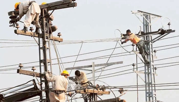 Technicians work on high-voltage power lines. — AFP/File