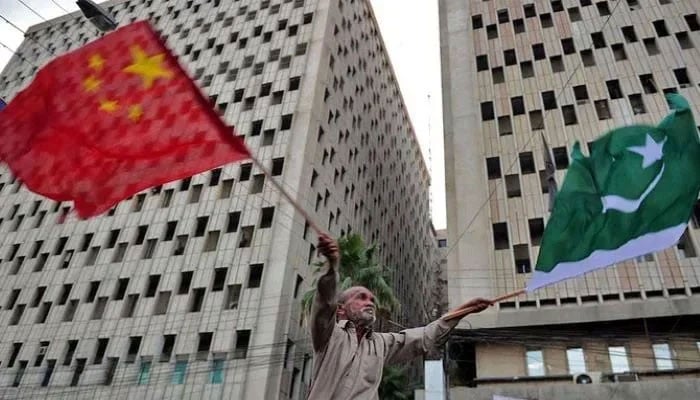 A Pakistani man waves Pakistani and Chinese national flags on a street in Karachi. — AFP/File