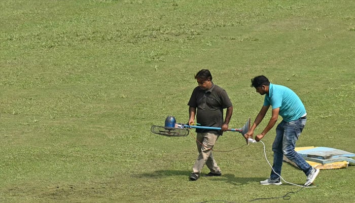 Groundsmen use a fan to dry a patch of wet outfield before the start of the one-off Test cricket match between Afghanistan and New Zealand. — AFP/file