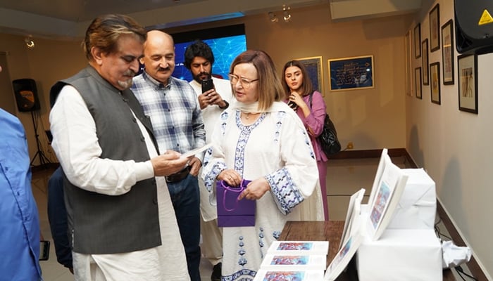 Former minister Jamal Shah looking at a painting printed on a book at the Connecting Dots Series exhibition of paintings and miniatures held at the Pakistan National Council of Arts (PNCA) and others are seen in this image released on September 11, 2024. — Facebook/@PNCAOfficial