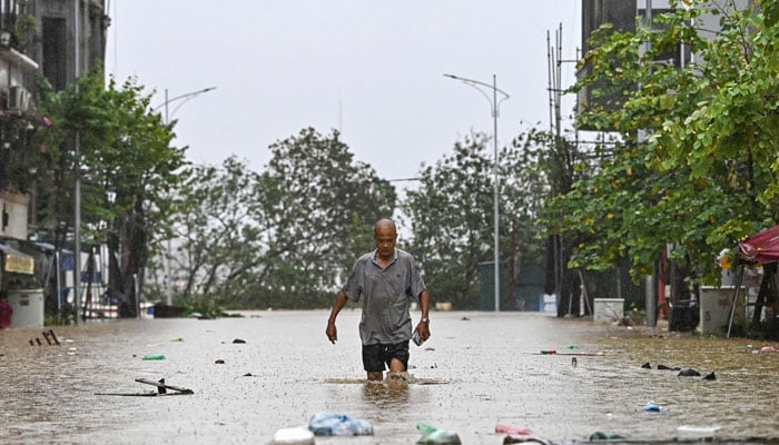 A man walks through flood waters in Hanoi on September 11, 2024. — AFP