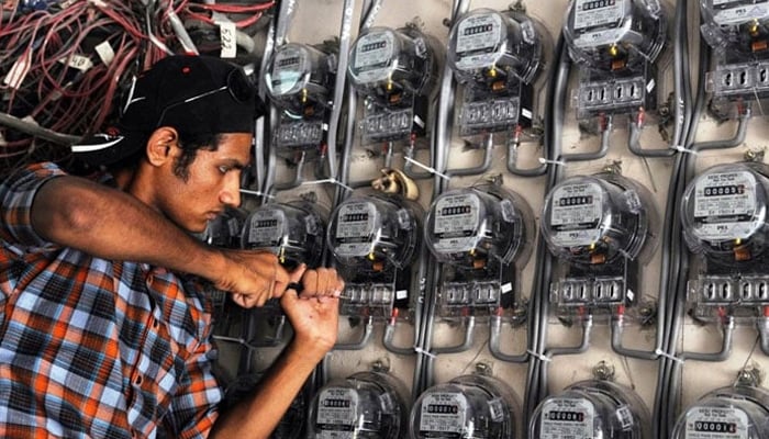 A technician fixes new electricity meters at a residential building in Pakistan. — AFP/File