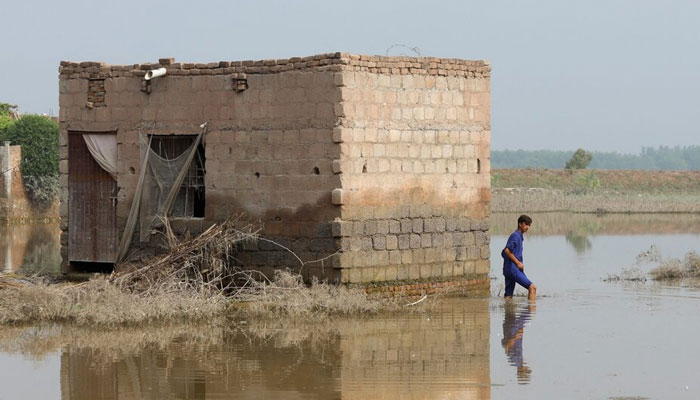 A boy walks beside a water-stained wall of a house, following rains and floods during the monsoon season in Nowshera. — Reuters/File