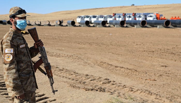 A security personnel stands guard near the pipes during the inauguration ceremony of the TAPI pipeline project, in the Tagtabazar district of Mary province, near the zero point between Turkmenistan and Afghanistan, on September 11, 2024. — AFP