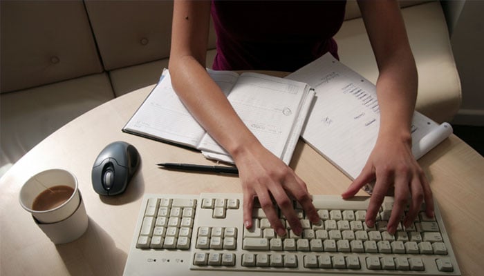 A woman works at her desk typing on a computer in this illustration picture taken January 9, 2005, —Reuters