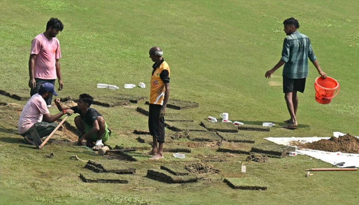 Groundsmen attempt to repair wet patches on the ground. — AFP/file