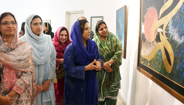 Visitors look at a painting during a calligraphy exhibition at Al-Hamra Hall, in Lahore on September 12, 2024. — Online