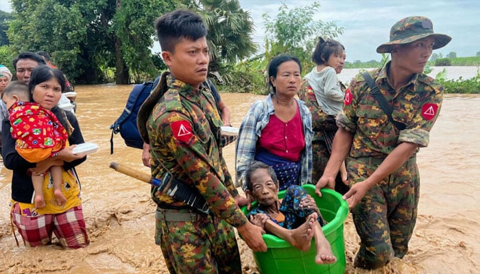 Two members of the Myanmar Junta rescue an old lady with other in the background.— AFP/file