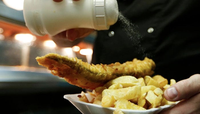 Manager Michael Upton adds salt to a customers fish and chips at Mr Fish restaurant in north London May 22, 2012. — Reuters