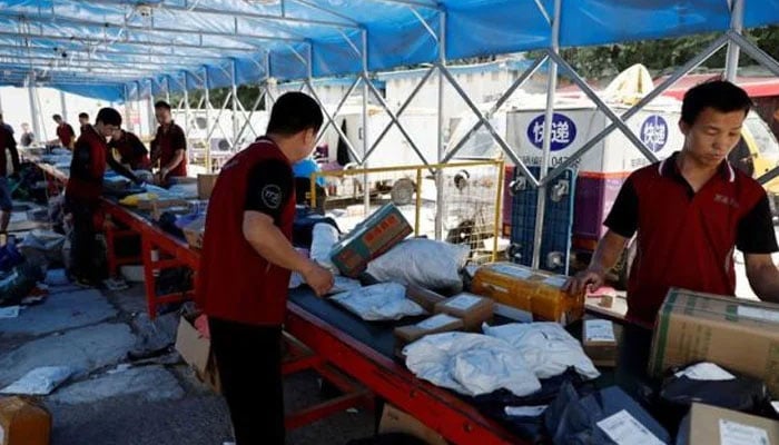 Delivery workers sort packages on a conveyor belt, ahead of the 618 shopping festival, at a logistics station in Beijing, China June 12, 2023. — Reuters