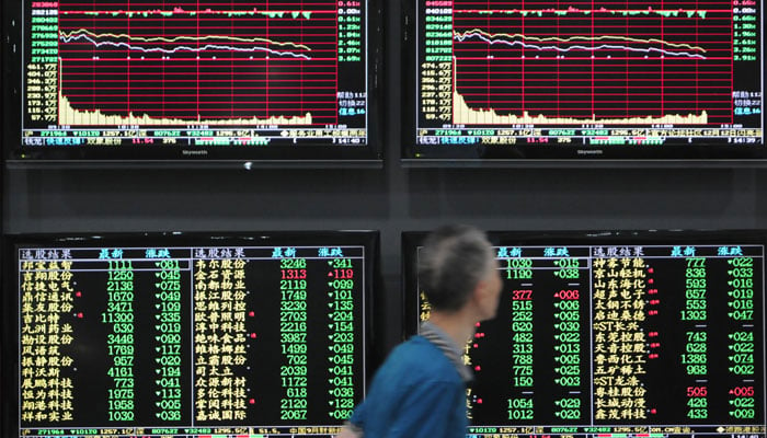 A man walks past screens showing stock information at a brokerage house in Jiujiang, Jiangxi province, China October 8, 2018. — Reuters