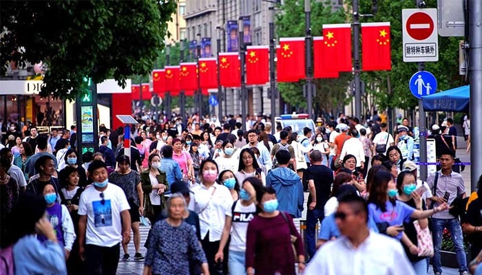 In this representational image, people walk along Nanjing Pedestrian Road, a main shopping area in Shanghai. — Reuters/File