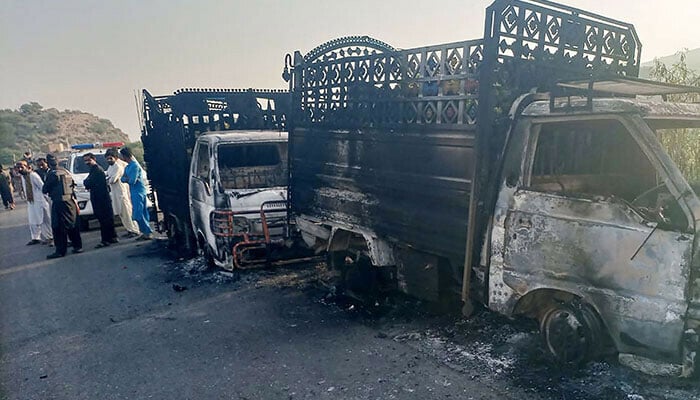 People stand near the charred vehicles at the shooting site on the national highway in Musakhail district, Balochistan on August 26, 2024. — AFP